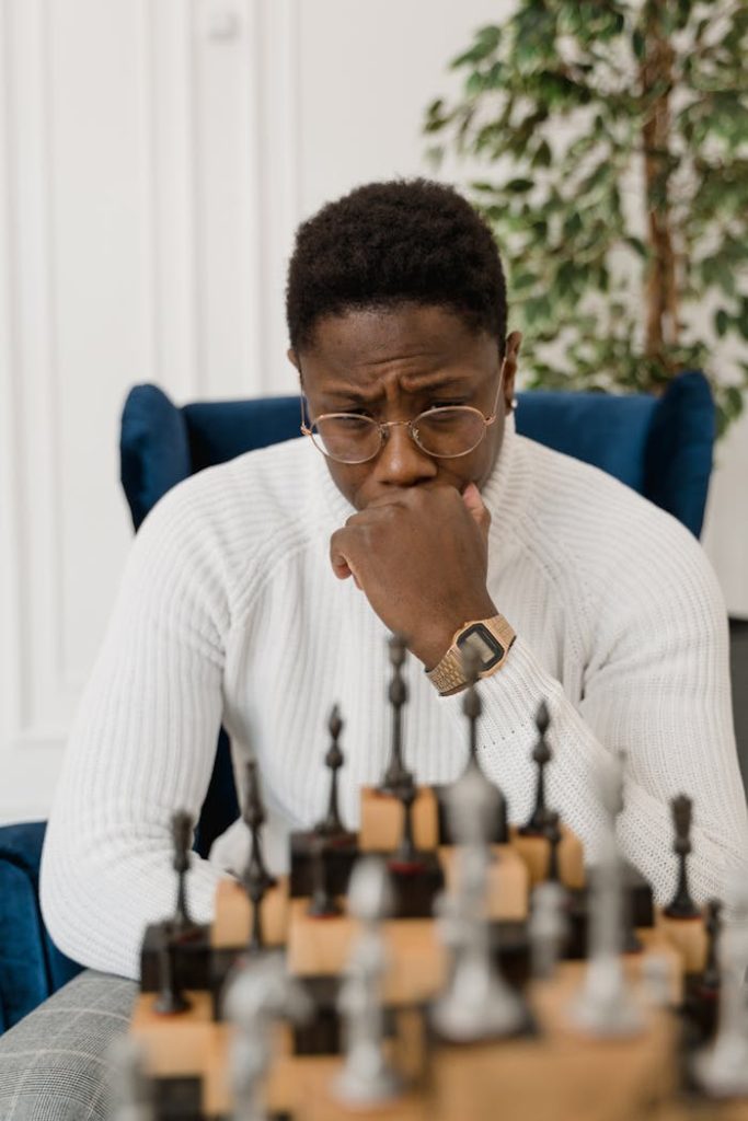 A Man Sitting at the Table with Chess Pieces